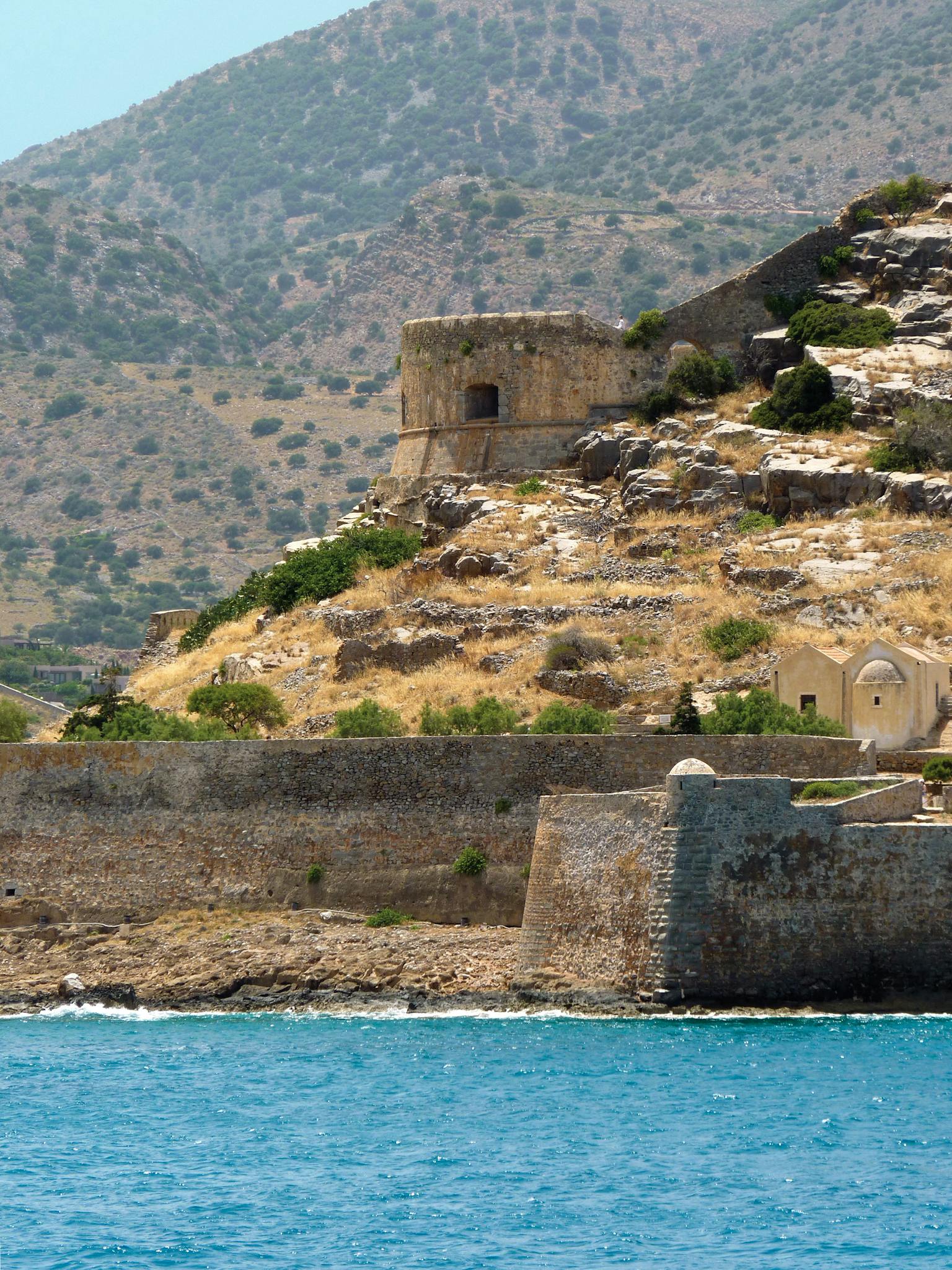 A scenic view of an ancient stone fortress on a coastal hillside by the sea.